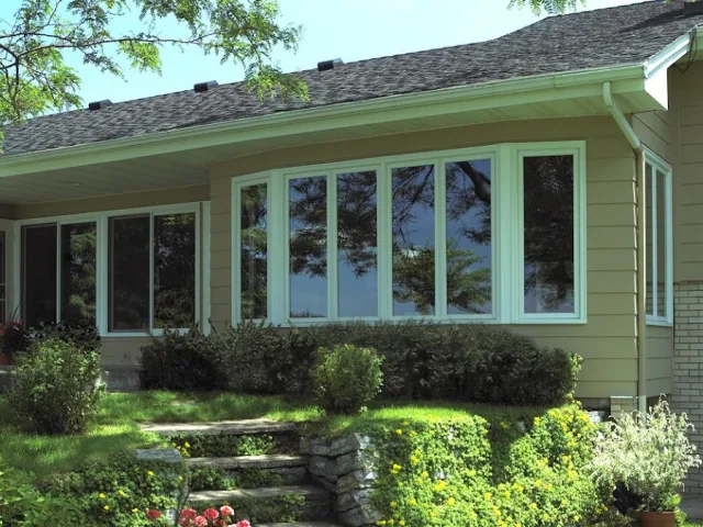 A home with a wide curved bow window above a green garden and stone steps