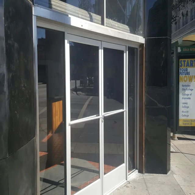 A pair of aluminum framed glass entry doors set into a dark stone building front