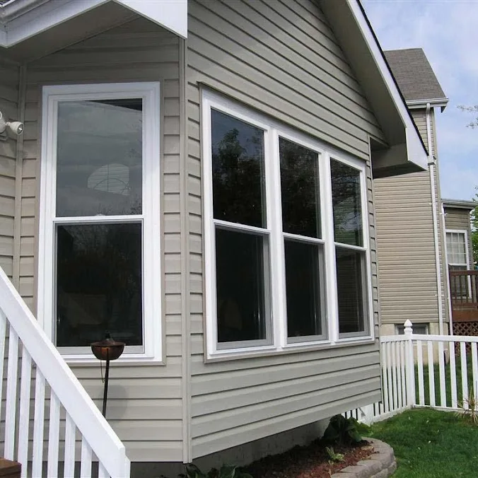White double hung windows on a tan siding wall beside white porch steps and a picket fence