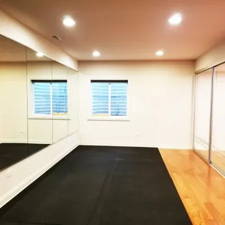 An empty room with mirror walls, mirrored sliding closet doors and rubber gym flooring