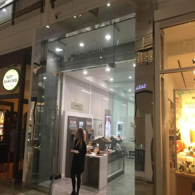 A side view of a mall shop with tall frameless glass panels beside the neighboring stores