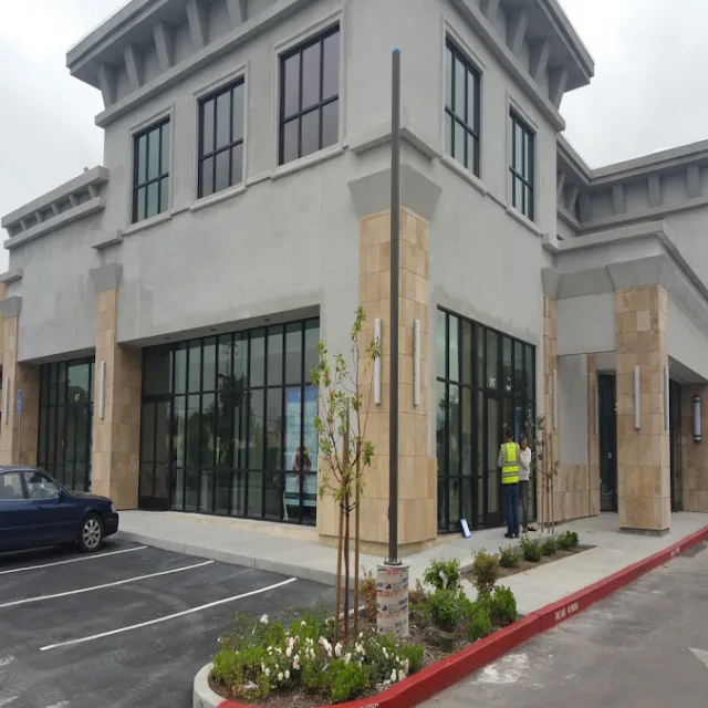 A new two story retail building with black framed storefront windows and a worker in a safety vest
