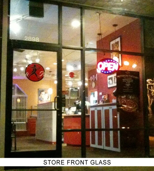 A restaurant storefront at night with a glass door and large windows, labeled store front glass