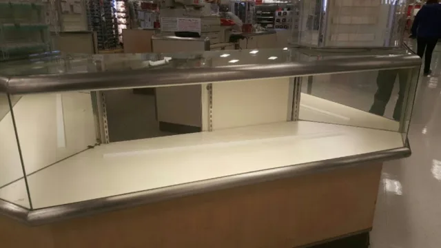 An empty retail display case with angled glass sides and a glass top