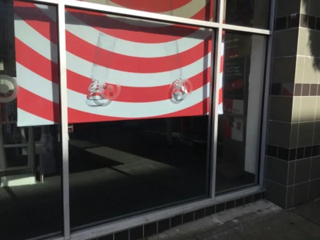 A large retail storefront window with a red and white striped banner hanging inside