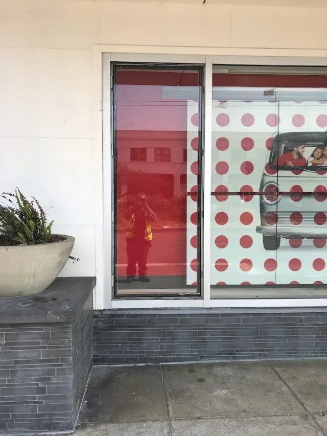 A retail storefront window with a large red dot graphic behind the glass