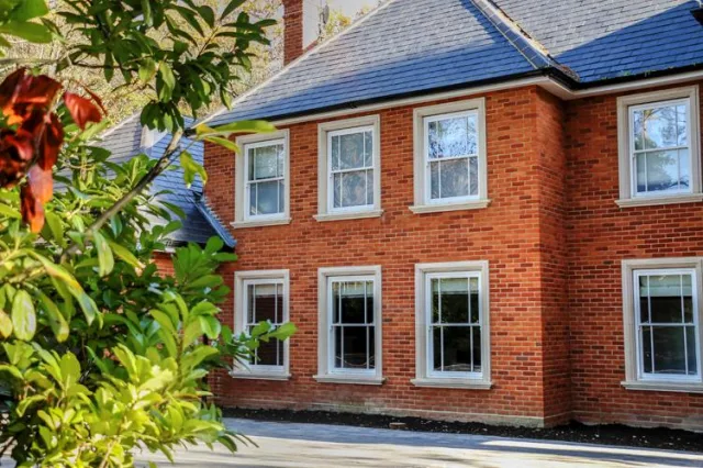 A two story red brick house with rows of white sash windows