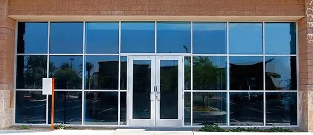 A storefront of dark framed glass panels with a pair of glass doors in the center