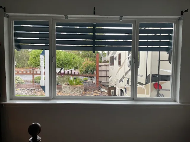 A wide three lite window with a louvered awning above it, seen from inside a room