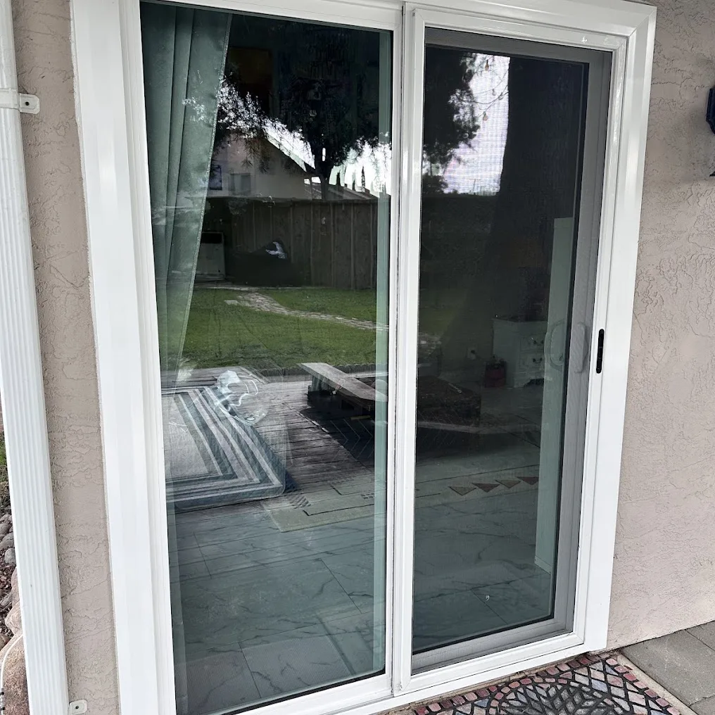 A white vinyl sliding patio door in a stucco wall, seen from the patio